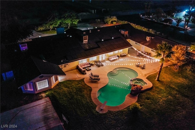 pool at twilight featuring a patio and an in ground hot tub