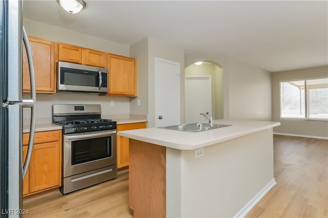 kitchen featuring light wood-type flooring, appliances with stainless steel finishes, sink, and an island with sink