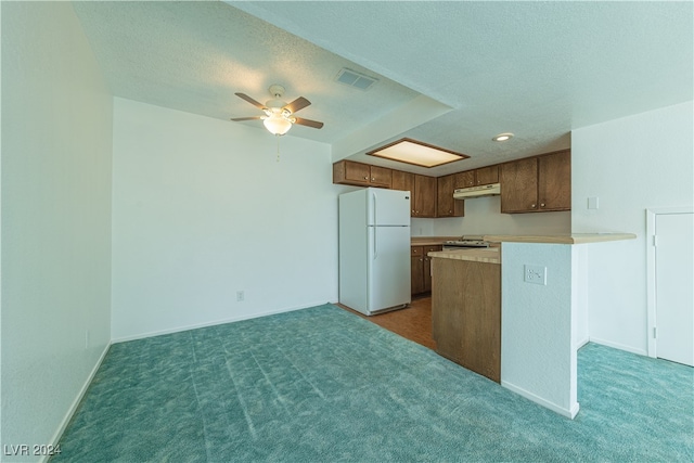 kitchen with a textured ceiling, white appliances, kitchen peninsula, dark colored carpet, and ceiling fan