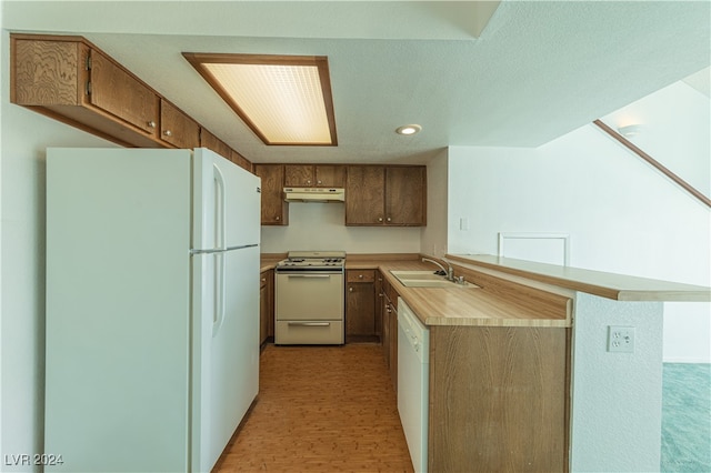 kitchen with kitchen peninsula, white appliances, and sink