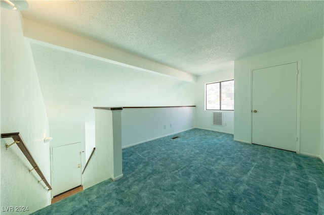 carpeted empty room featuring a textured ceiling