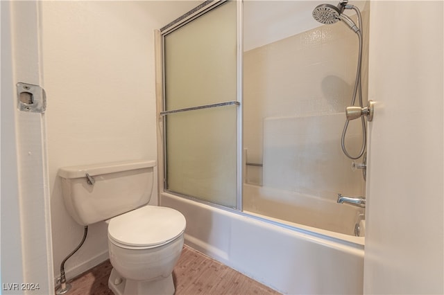 bathroom featuring toilet, hardwood / wood-style floors, and shower / bath combination with glass door