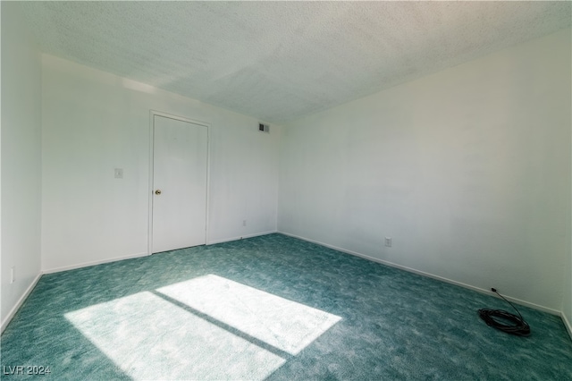 unfurnished room featuring a textured ceiling and dark carpet