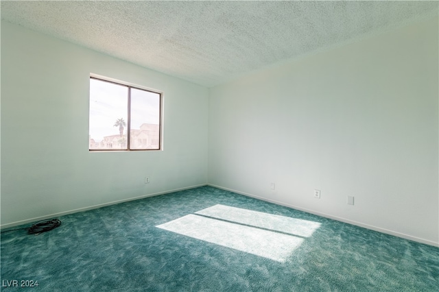 spare room featuring a textured ceiling and dark carpet