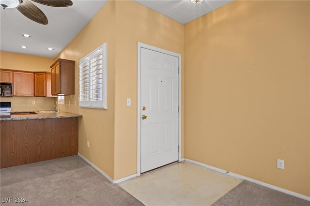 kitchen with stove, light carpet, and ceiling fan