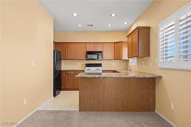 kitchen with kitchen peninsula, sink, light stone countertops, and black appliances