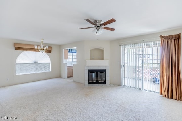 unfurnished living room featuring a fireplace, ceiling fan with notable chandelier, and light carpet