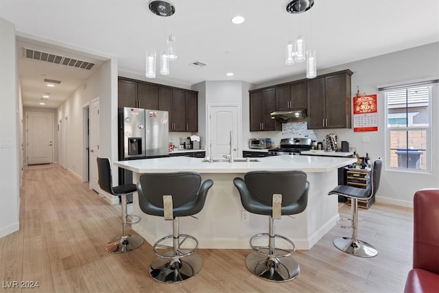 kitchen with dark brown cabinetry, pendant lighting, light hardwood / wood-style floors, and appliances with stainless steel finishes