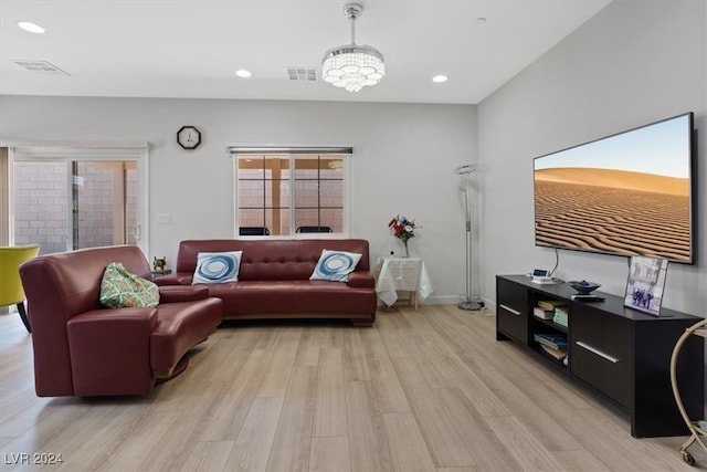 living room with light hardwood / wood-style floors and an inviting chandelier