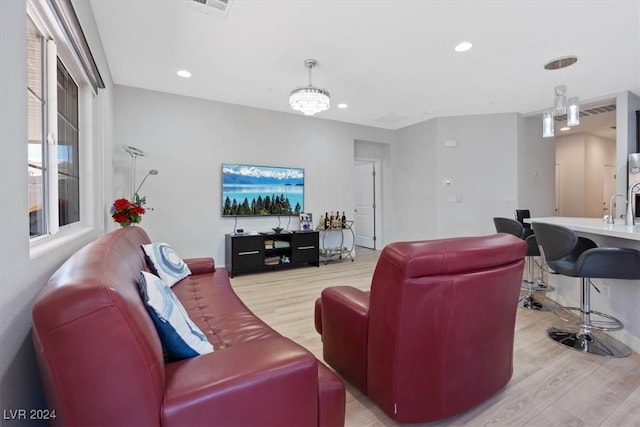 living room featuring sink, an inviting chandelier, and light wood-type flooring