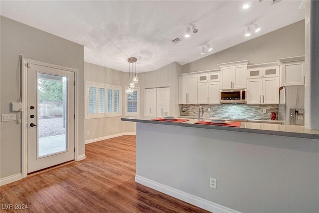 kitchen with white cabinets, decorative backsplash, lofted ceiling, and stainless steel appliances