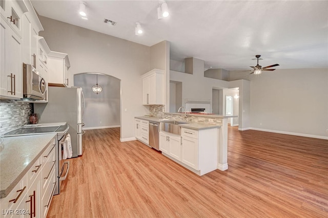 kitchen with white cabinets, sink, tasteful backsplash, kitchen peninsula, and stainless steel appliances