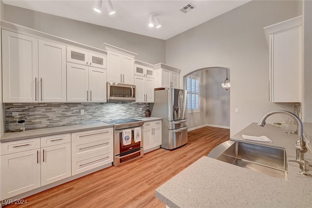 kitchen featuring appliances with stainless steel finishes, backsplash, sink, light hardwood / wood-style floors, and white cabinetry