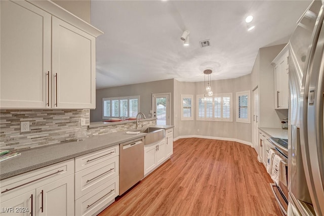 kitchen featuring pendant lighting, white cabinets, sink, appliances with stainless steel finishes, and light stone counters