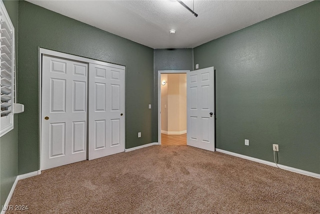 unfurnished bedroom with carpet flooring, a textured ceiling, and a closet