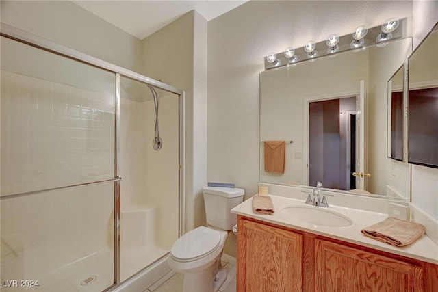 bathroom with tile patterned flooring, vanity, toilet, and a shower with door