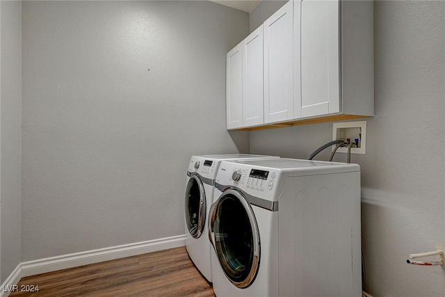 laundry room featuring washing machine and dryer, hardwood / wood-style floors, and cabinets