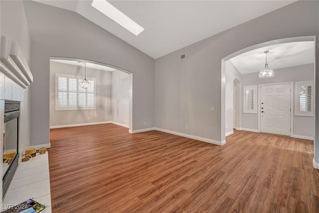 unfurnished living room featuring wood-type flooring, lofted ceiling, and a notable chandelier