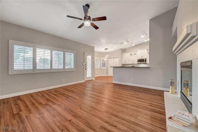 unfurnished living room featuring ceiling fan, light hardwood / wood-style flooring, and vaulted ceiling