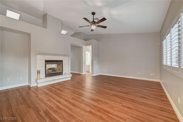 unfurnished living room featuring ceiling fan, light hardwood / wood-style flooring, a fireplace, and vaulted ceiling