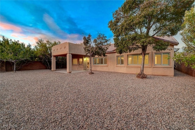 back house at dusk with a patio area