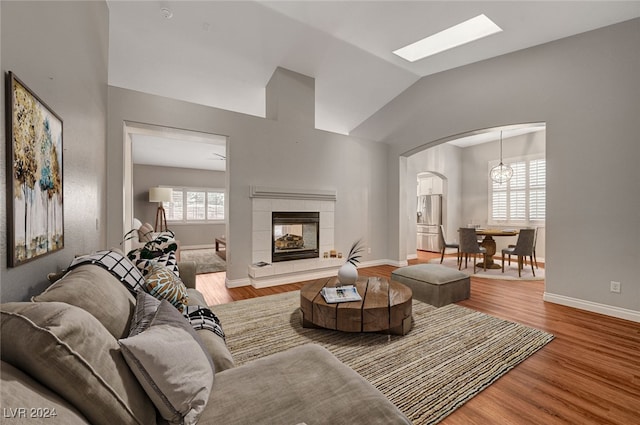 living room featuring a tiled fireplace, lofted ceiling, and hardwood / wood-style flooring