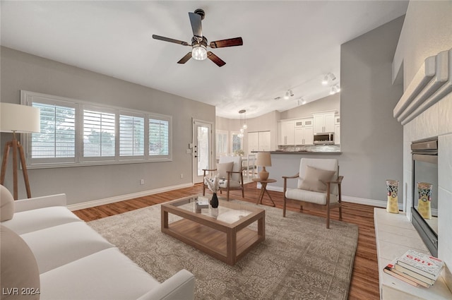 living room with ceiling fan, light hardwood / wood-style floors, and lofted ceiling