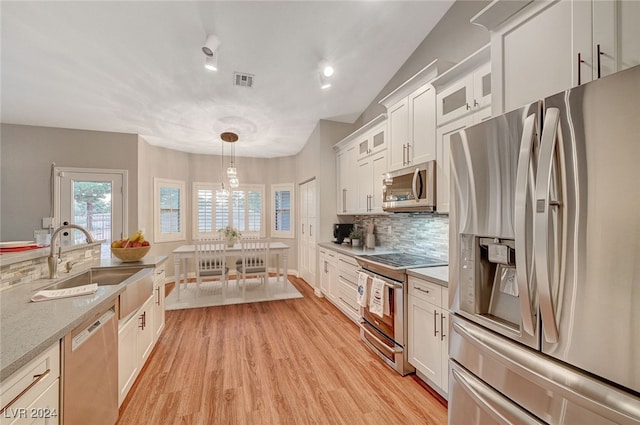 kitchen with pendant lighting, sink, white cabinets, and stainless steel appliances