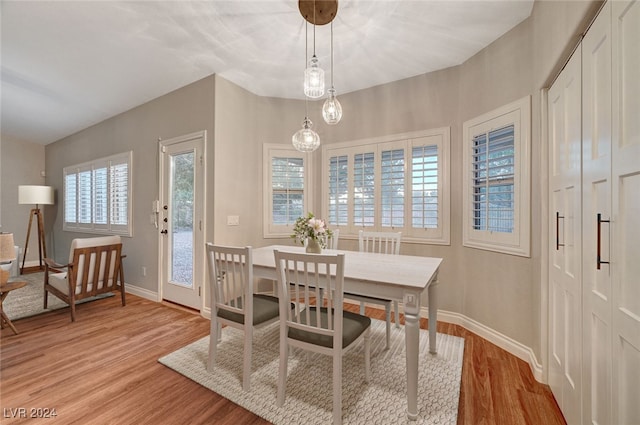 dining space with light hardwood / wood-style floors and an inviting chandelier