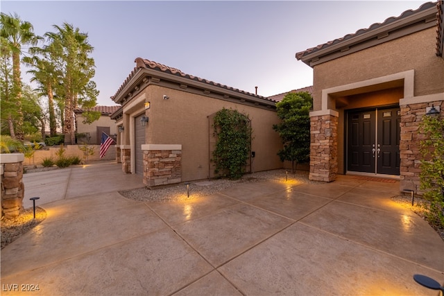 patio terrace at dusk featuring a garage