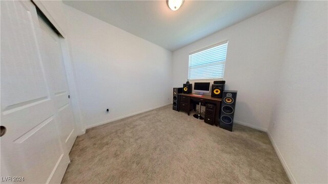 carpeted office featuring lofted ceiling