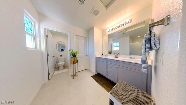 bathroom featuring vanity, tile patterned floors, a healthy amount of sunlight, and toilet