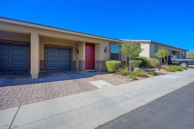 2675 Chinaberry Hill St, Laughlin, NV 89029 - ranch-style home with stucco siding, decorative driveway, a garage, and stone siding