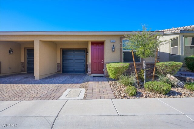 2675 Chinaberry Hill St, Laughlin, NV 89029 - property entrance featuring stucco siding, decorative driveway, an attached garage, and stone siding