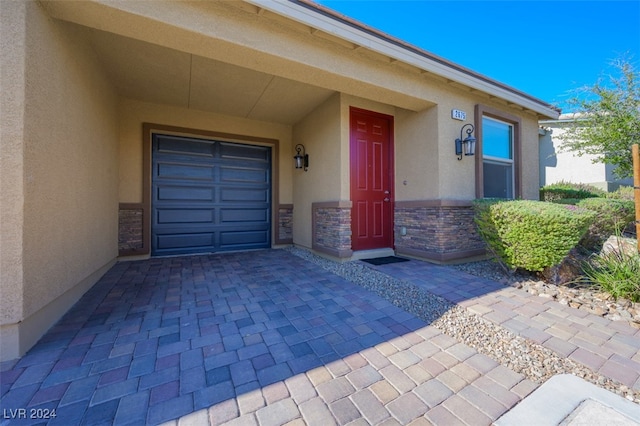 2675 Chinaberry Hill St, Laughlin, NV 89029 - property entrance featuring stucco siding, stone siding, decorative driveway, and a garage