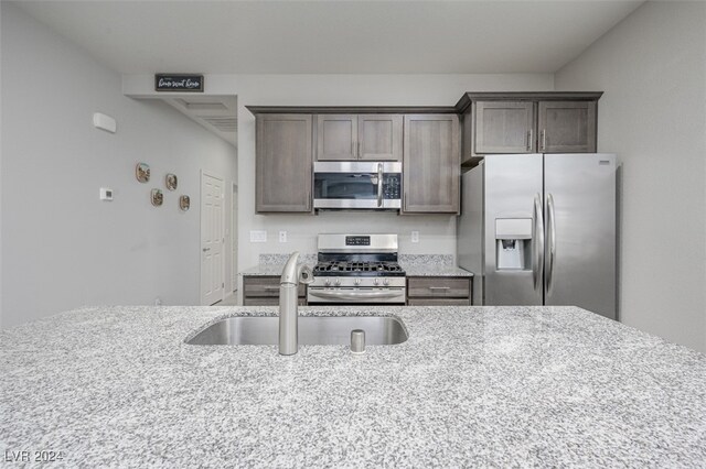 2675 Chinaberry Hill St, Laughlin, NV 89029 - kitchen with appliances with stainless steel finishes, a sink, light stone countertops, and dark brown cabinets