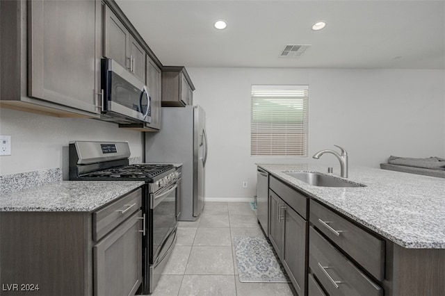 kitchen featuring light stone countertops, appliances with stainless steel finishes, light tile patterned floors, and sink