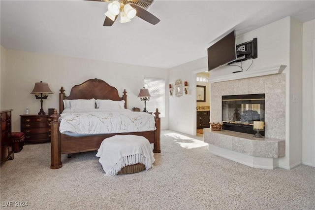 carpeted bedroom with ensuite bath, ceiling fan, and a fireplace