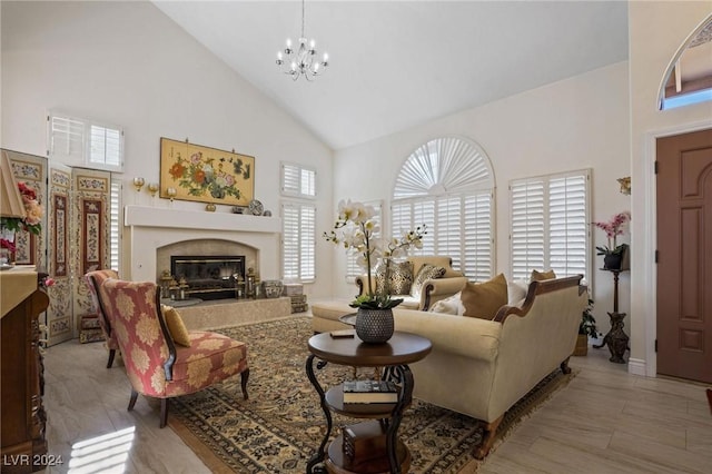 living room featuring a high end fireplace, light hardwood / wood-style flooring, high vaulted ceiling, and a notable chandelier