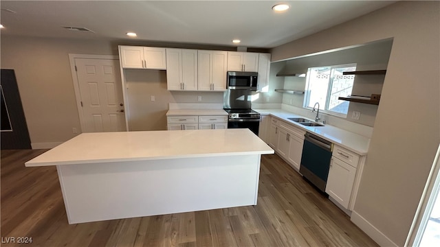 kitchen with sink, a kitchen island, white cabinetry, and appliances with stainless steel finishes