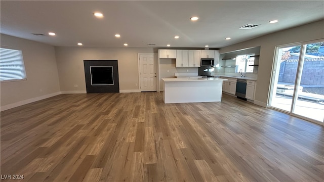 kitchen featuring dishwasher, sink, white cabinets, a kitchen island, and light hardwood / wood-style floors