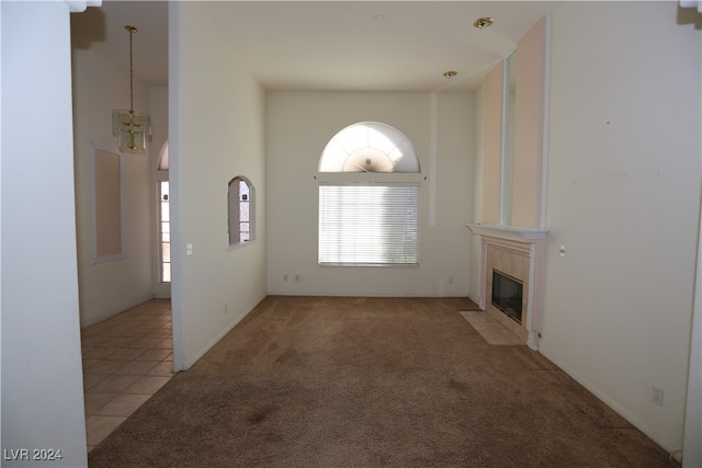 unfurnished living room featuring a chandelier and light colored carpet