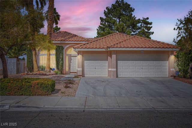 mediterranean / spanish-style home featuring a tile roof, stucco siding, concrete driveway, and a garage