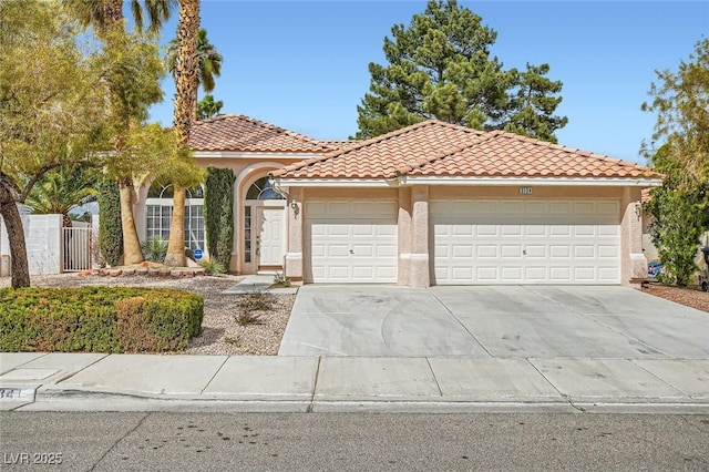 mediterranean / spanish-style house with stucco siding, driveway, an attached garage, and a tiled roof