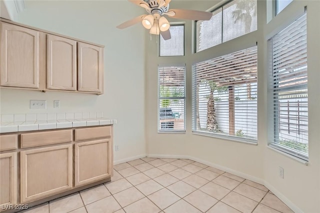 kitchen featuring plenty of natural light, light brown cabinets, a ceiling fan, and tile counters