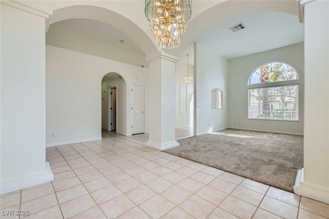 empty room featuring an inviting chandelier, light tile patterned floors, visible vents, and light carpet