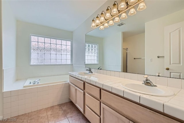 bathroom featuring tile patterned floors, a bath, double vanity, and a sink