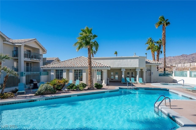 view of swimming pool featuring a mountain view, a community hot tub, and a patio area