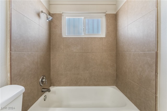 bathroom featuring toilet and tiled shower / bath