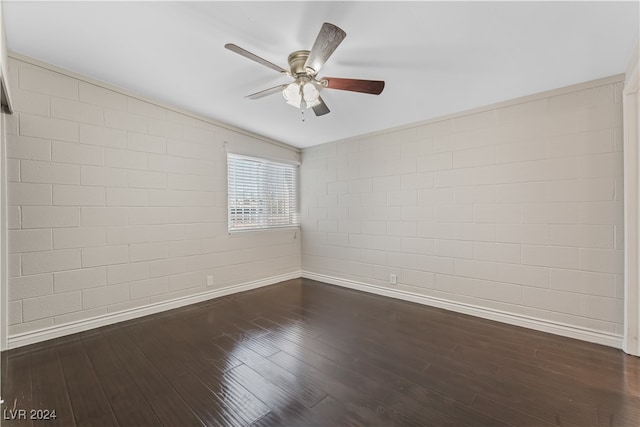 spare room with ceiling fan, dark hardwood / wood-style flooring, and brick wall